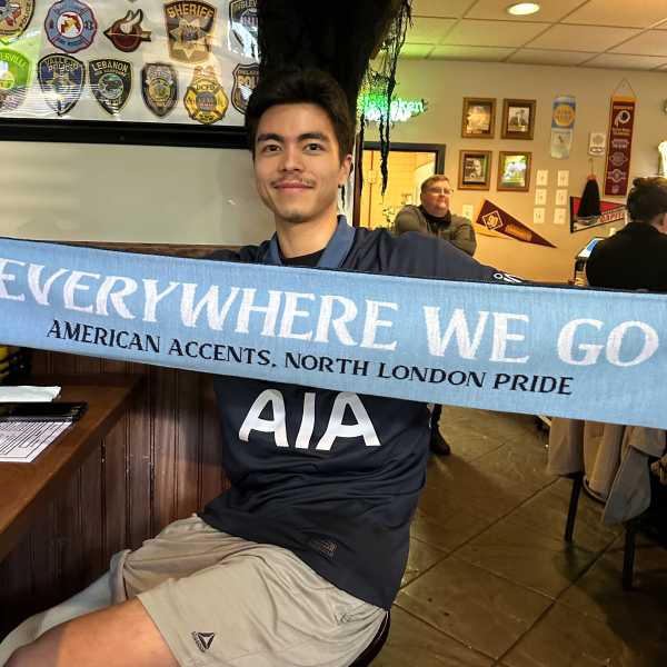 A man holding one side of the DC Spurs scarf up at a bar table.